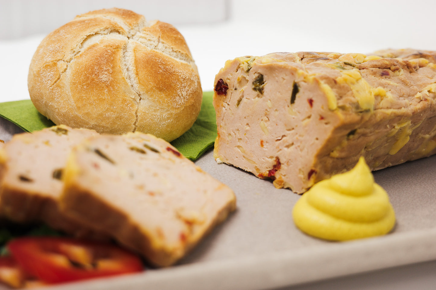 Der vegane Chili Cheese Leberkäse angerichtet mit Senf und einer Semmel.