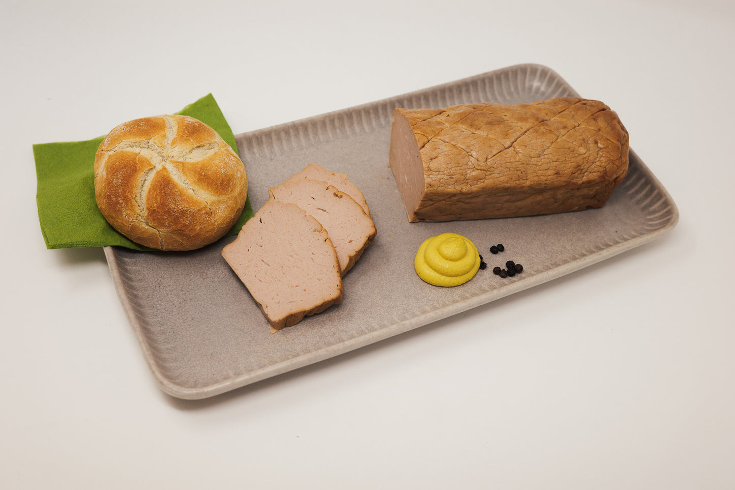 JackFood Leberkäse natur abgeschnitten und neben einer Semmel und Senf platziert.