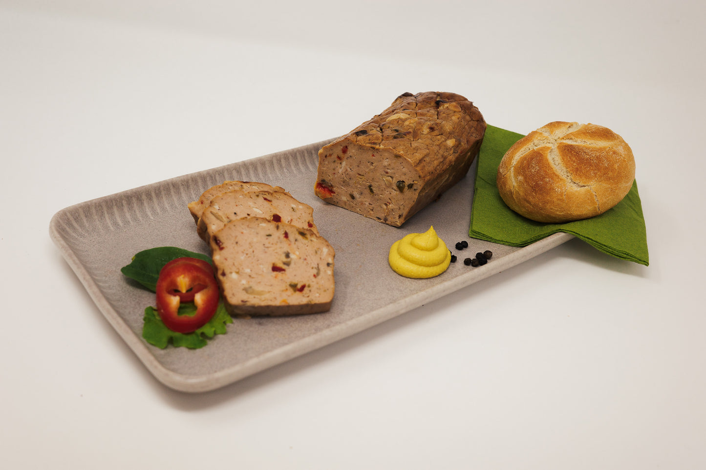 Pizza Leberkäse teilweise aufgeschnitten und auf einen Teller mit Senf und Semmel angerichtet.