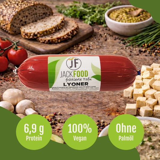 Die pflanzliche Lyoner Alternative von JackFood mit frittierten Tofu. Im Hintergrund sind Tofuwürfel, Tomaten und Brot.