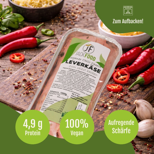 JackFoods veganer Chilli-Cheese Leberkäse zum Aufbacken in seiner Aluschale und im Hintergrund sind noch Streukäse und rote Chilis.