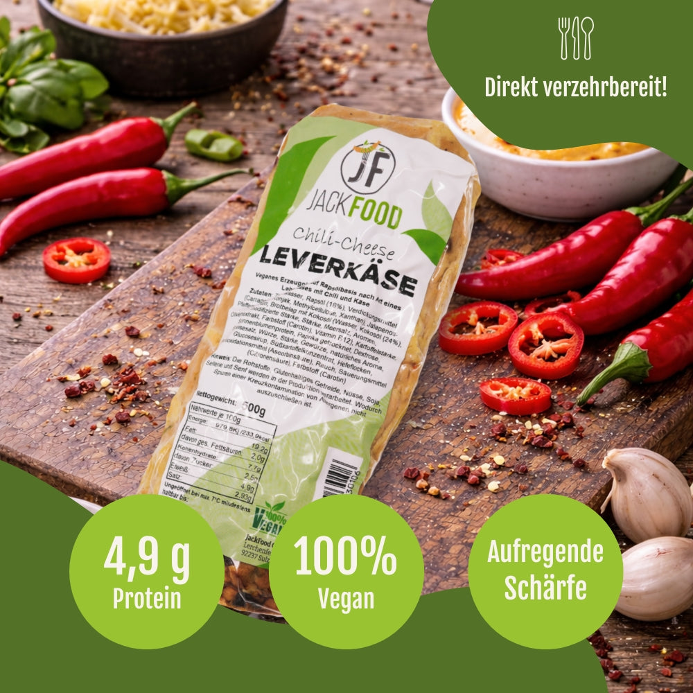 Der gebackene vegane Chili Cheese Leberkäse mit Chilis und Knoblauch im Hintergrund.